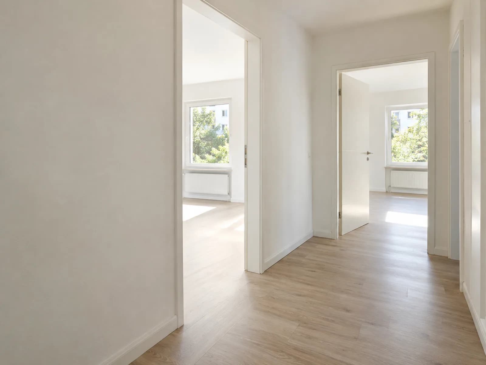 Leere, frisch sanierte Wohnung mit hellem Boden und offenen Türen