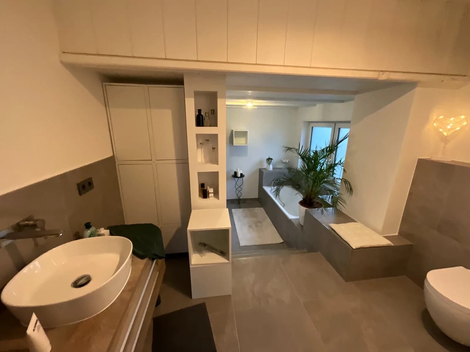 Gesamtansicht des sanierten Badezimmers mit Waschtisch, Badewanne und WC