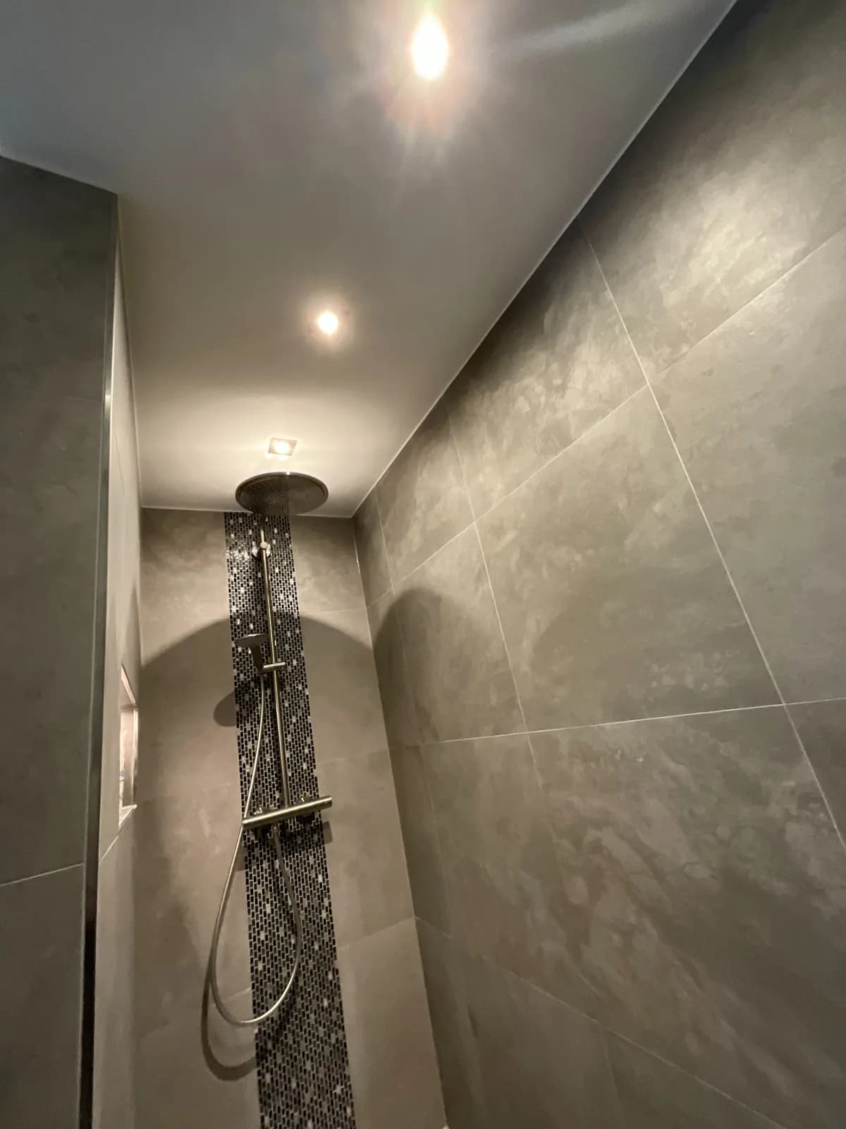Großformatig geflieste Dusche mit Regendusche und Mosaikakzent