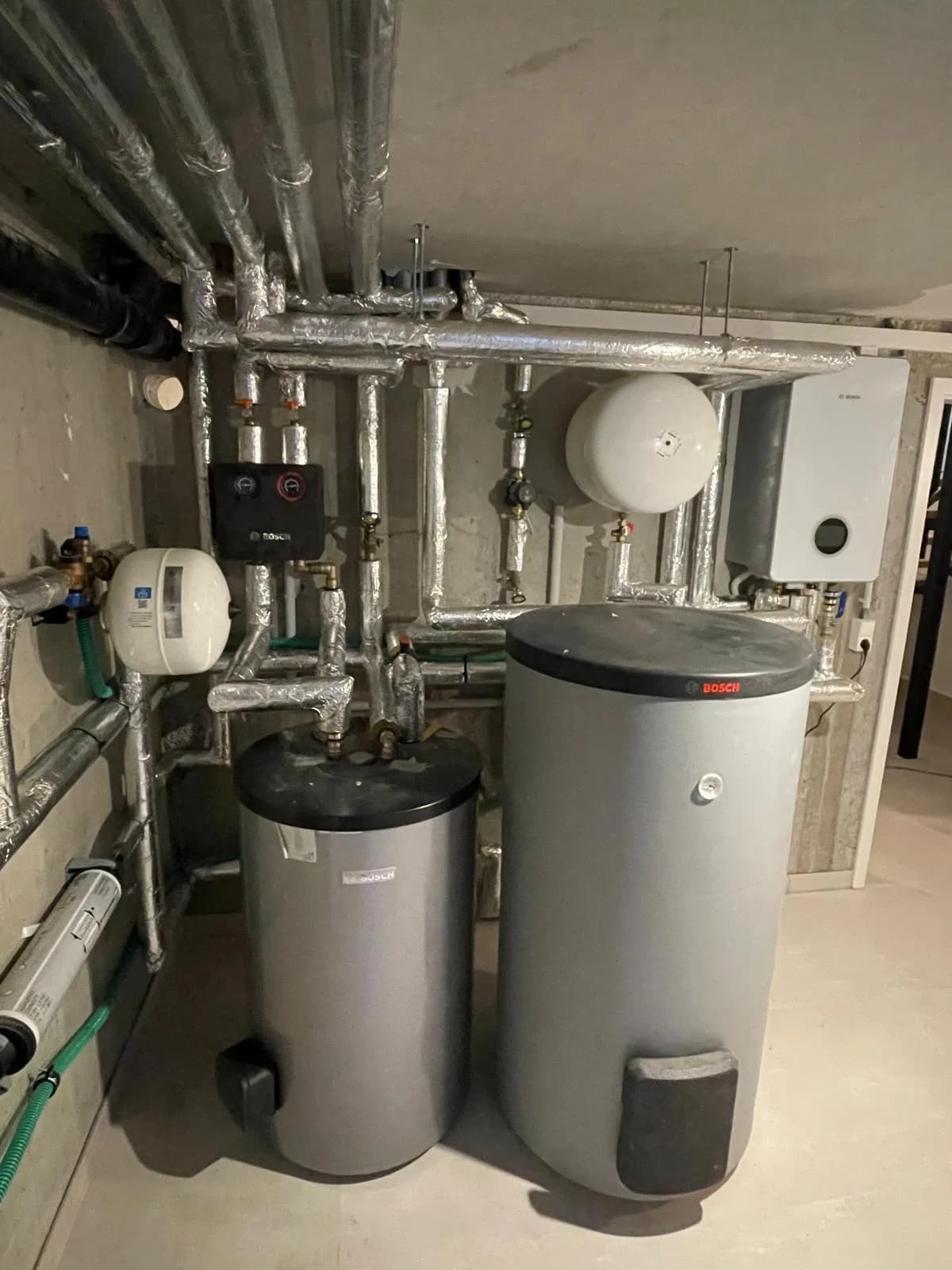 Bosch Wärmepumpenanlage im Technikraum mit Speichern, Ausdehnungsgefäßen und gedämmten Rohrleitungen