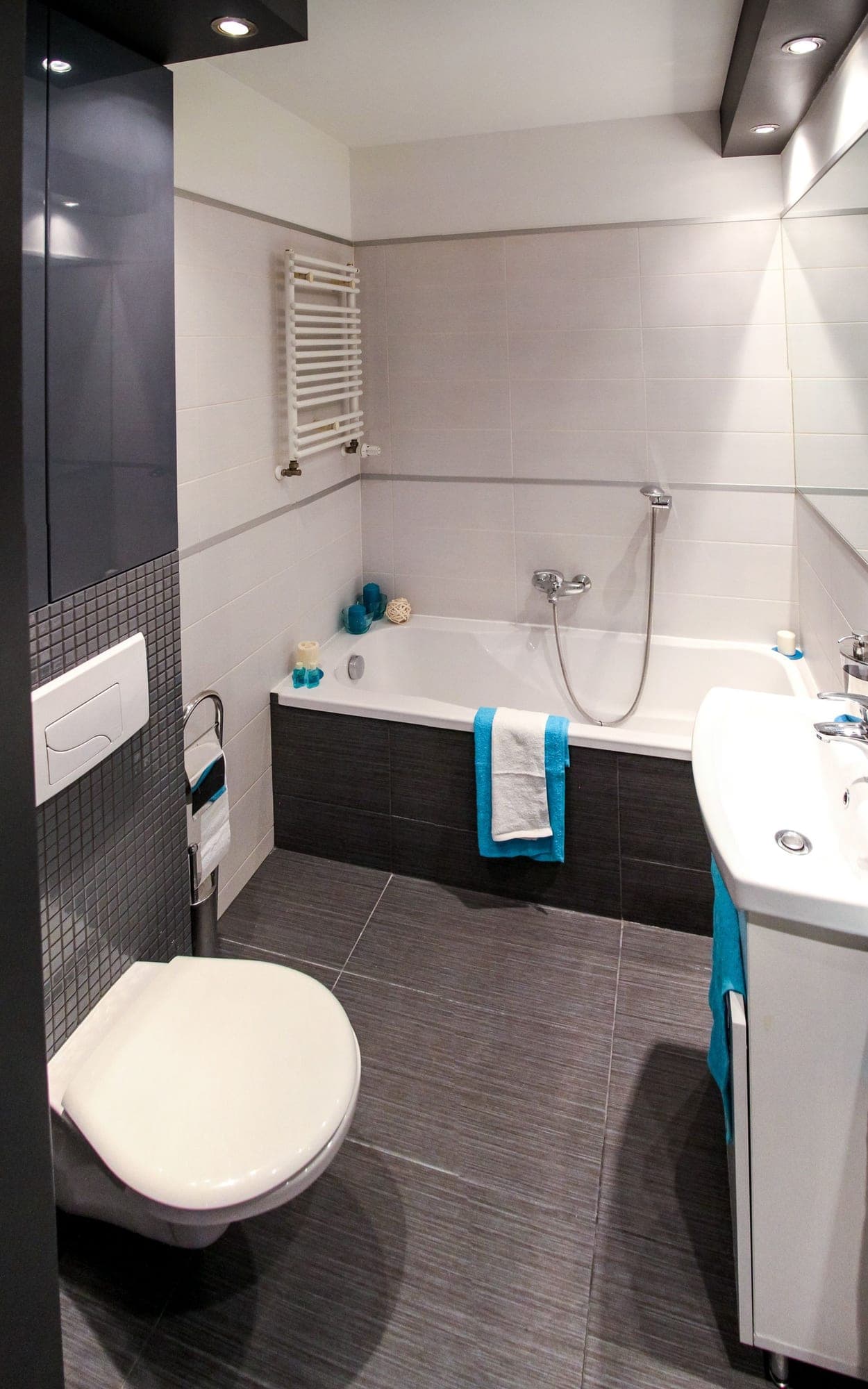 Kleines Bad mit Badewanne, Wand-WC und grauen Bodenfliesen